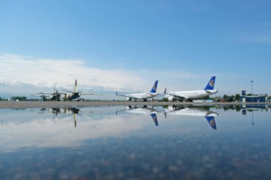 Almaty / Kazakistan - 04.23.2019: Ulusal havayolu şirketi Air Astana 'nın uçakları pistte, suda bir yansımayla