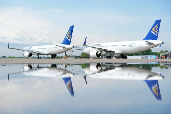 Almaty / Kazakistan - 04.23.2019: Ulusal havayolu şirketi Air Astana 'nın uçakları pistte, suda bir yansımayla