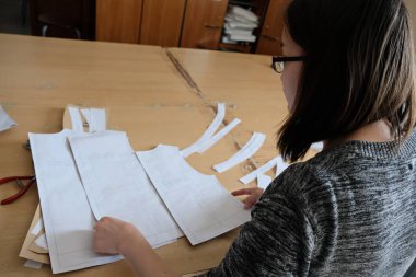 Almaty / Kazakistan - 04.09.2019: Şehir giyim üretiminde küçük işletme. Çalışanlar, mavi üniformaları ütülemek ve dikmek için desen hazırlıyorlar..