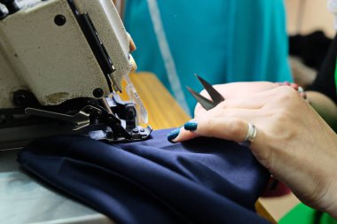 Almaty / Kazakistan - 04.09.2019: Şehir giyim üretiminde küçük işletme. Çalışanlar, mavi üniformaları ütülemek ve dikmek için desen hazırlıyorlar..