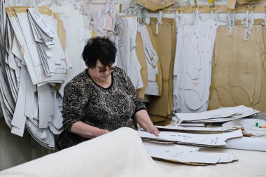 Almaty / Kazakistan - 04.09.2019: Şehir giyim üretiminde küçük işletme. Çalışanlar, mavi üniformaları ütülemek ve dikmek için desen hazırlıyorlar..