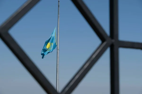 哈萨克斯坦共和国国旗通过金属格栅在天空中飘扬 — 图库照片