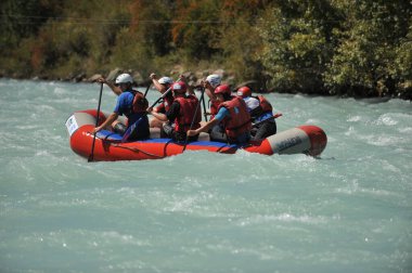 Almaty / Kazakistan - 09.03.2011: Sallar ve şişme botlarla bir dağ nehrinde rafting. Bir grup insan dalgalarla kürekleri kontrol ediyor.