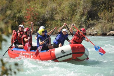 Almaty / Kazakistan - 09.03.2011: Sallar ve şişme botlarla bir dağ nehrinde rafting. Bir grup insan dalgalarla kürekleri kontrol ediyor.