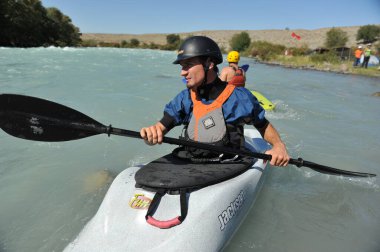 Almaty / Kazakistan - 09.03.2011: Dağlık nehir kayağında rafting. Bir adam akıntıyla yüzer ve küreği kontrol eder.
