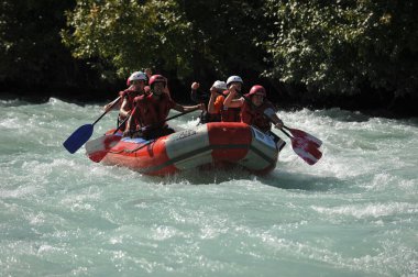 Almaty / Kazakistan - 09.03.2011: Sallar ve şişme botlarla bir dağ nehrinde rafting. Bir grup insan dalgalarla kürekleri kontrol ediyor.