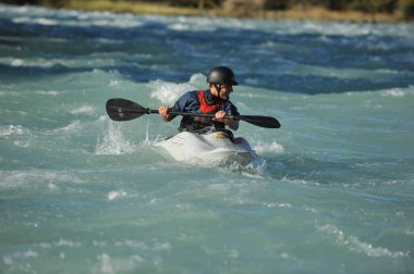 Almaty / Kazakistan - 09.03.2011: Dağlık nehir kayağında rafting. Bir adam akıntıyla yüzer ve küreği kontrol eder.