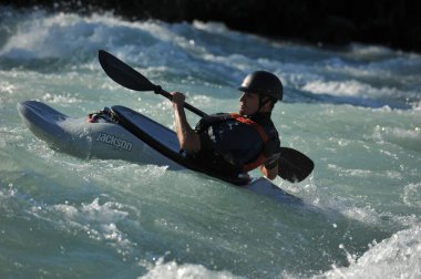 Almaty / Kazakistan - 09.03.2011: Dağlık nehir kayağında rafting. Bir adam akıntıyla yüzer ve küreği kontrol eder.