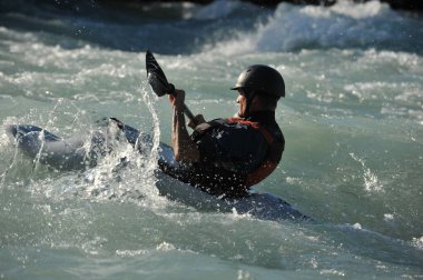 Almaty / Kazakistan - 09.03.2011: Dağlık nehir kayağında rafting. Bir adam akıntıyla yüzer ve küreği kontrol eder.