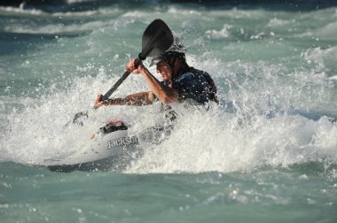 Almaty / Kazakistan - 09.03.2011: Dağlık nehir kayağında rafting. Bir adam akıntıyla yüzer ve küreği kontrol eder.