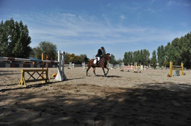 Almaty bölgesi / Kazakistan - 10.08.2011: Atlama yarışı. Atletler ve atları tahta engellerle dolu bir platformda antrenman yapıyorlar.