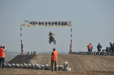 Almaty / Kazakistan - 10.22.2011: Motokros yarışmaları. Sporcular tekerleklerden yapılmış engellerle pisti geçiyorlar