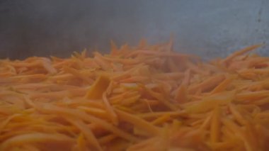 Pilav yapmak için büyük bir kazanda havuç kızartmak. Açık havada yemek yapmak..