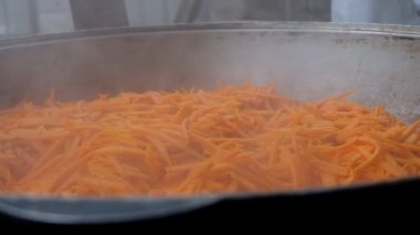 Pilav yapmak için büyük bir kazanda havuç kızartmak. Açık havada yemek yapmak..