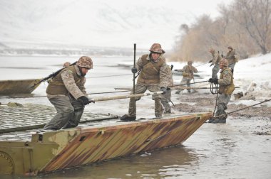 Almaty bölgesi / Kazakistan - 02.29.2012: Askerler nehri geçmek için metal bir yapı oluşturuyorlar. Kazakistan mühendislik birliklerinin tatbikatları.
