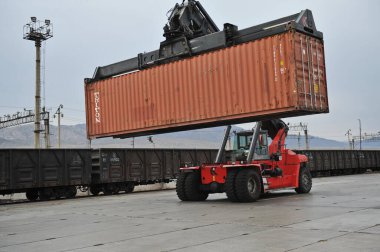 Almaty bölgesi / Kazakistan - 04.11.2012: Bir vinç sıralama konteynırına sahip özel ulaşım. Demiryolu kavşağı