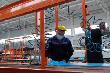 Almaty / Kazakistan - 08.18.2020: Metal yapıların üretimi için tesis. İşçiler ürünü özel ekipmanlar üzerine monte ediyor. 