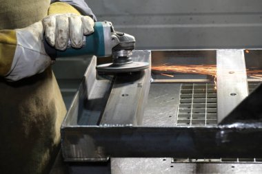 Almaty / Kazakistan - 08.18.2020: Fabrikada metal ürünlerinin öğütülmesi. Bir işçi elinde bir alet tutar..