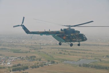 Almaty / Kazakistan - 08.25.2020: Konut binaları, çeşitli altyapı ve tarım arazileri olan bir şehir üzerinde askeri helikopterin kalkışı.