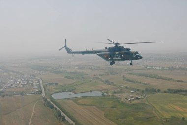 Almaty / Kazakistan - 08.25.2020: Konut binaları, çeşitli altyapı ve tarım arazileri olan bir şehir üzerinde askeri helikopterin kalkışı.