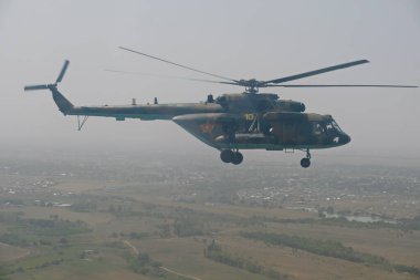 Almaty / Kazakistan - 08.25.2020: Konut binaları, çeşitli altyapı ve tarım arazileri olan bir şehir üzerinde askeri helikopterin kalkışı.