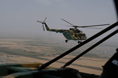 Almaty / Kazakistan - 08.25.2020: Konut binaları, çeşitli altyapı ve tarım arazileri olan bir şehir üzerinde askeri helikopterin kalkışı.