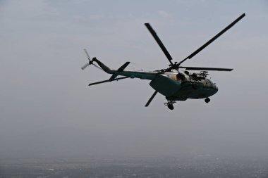 Almaty / Kazakistan - 08.25.2020: Konut binaları, çeşitli altyapı ve tarım arazileri olan bir şehir üzerinde askeri helikopterin kalkışı.