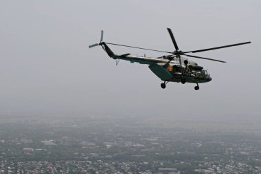Almaty / Kazakistan - 08.25.2020: Konut binaları, çeşitli altyapı ve tarım arazileri olan bir şehir üzerinde askeri helikopterin kalkışı.
