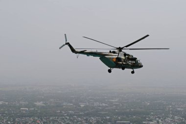 Almaty / Kazakistan - 08.25.2020: Konut binaları, çeşitli altyapı ve tarım arazileri olan bir şehir üzerinde askeri helikopterin kalkışı.