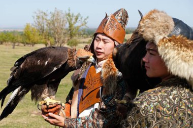 Almaty / Kazakistan - 09.23.2020: Kartalların elinde tutulan ulusal kostümler giymiş iki genç.