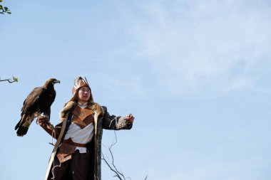 Almaty / Kazakistan - 09.23.2020: Kazak milli kostümlü bir genç elinde evcil bir altın kartal tutuyor.