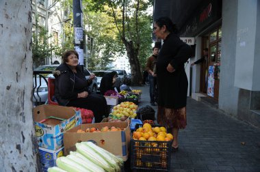 Gürcistan / Tiflis - 10.26.2012: Bir kadın sokak köşesinde çeşitli taze sebzeler satıyor.