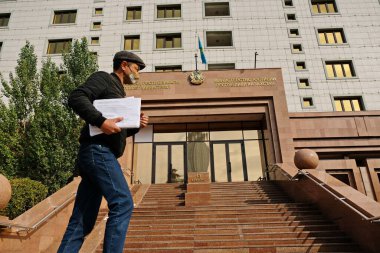 Nur-Sultan / Kazakistan - 10.02.2020: Elinde bir tomar belge olan bir adam Kazakistan Adalet Bakanlığı 'nın ana girişinden yürüyerek geçti