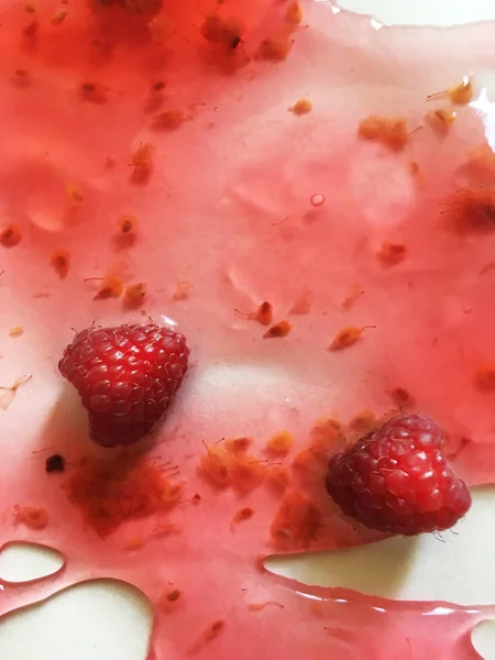 Beyaz bir arka plan üzerinde ahududu jöle yüzen derin doymuş ahududu rengi olgun sulu ahududu