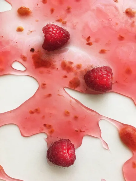 Beyaz bir arka plan üzerinde ahududu jöle yüzen derin doymuş ahududu rengi olgun sulu ahududu