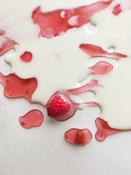 Atasözü Süt nehirleri jöle bankalar görsel bir şekillenme olarak beyaz bir arka plan üzerinde süt ile ahududu jöle yüzen derin doymuş ahududu rengi Olgun sulu ahududu