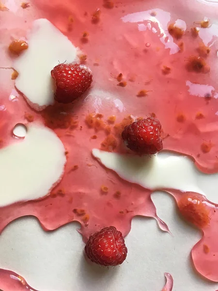 Atasözü Süt nehirleri jöle bankalar görsel bir şekillenme olarak beyaz bir arka plan üzerinde süt ile ahududu jöle yüzen derin doymuş ahududu rengi Olgun sulu ahududu