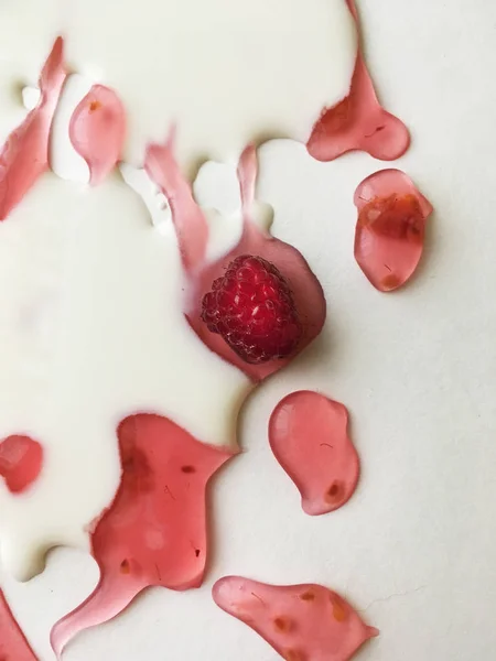 Atasözü Süt nehirleri jöle bankalar görsel bir şekillenme olarak beyaz bir arka plan üzerinde süt ile ahududu jöle yüzen derin doymuş ahududu rengi Olgun sulu ahududu