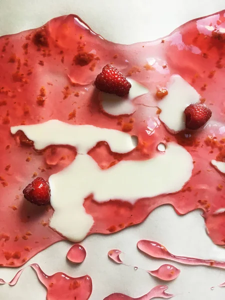 Atasözü Süt nehirleri jöle bankalar görsel bir şekillenme olarak beyaz bir arka plan üzerinde süt ile ahududu jöle yüzen derin doymuş ahududu rengi Olgun sulu ahududu