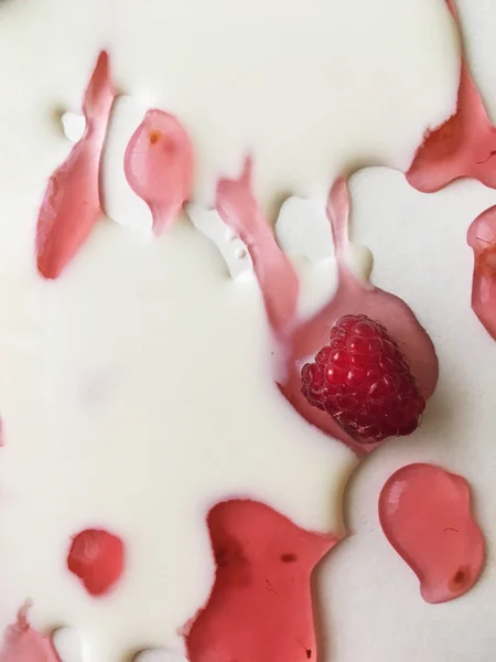 Atasözü Süt nehirleri jöle bankalar görsel bir şekillenme olarak beyaz bir arka plan üzerinde süt ile ahududu jöle yüzen derin doymuş ahududu rengi Olgun sulu ahududu