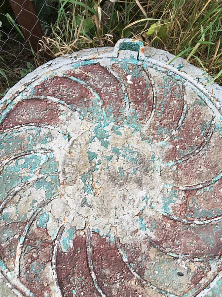 Kentsel yapıların bir unsuru olarak kahverengi, yeşil, gri boya katmanları ile kaplı harap bir rögar üzerinde eski kanalizasyon rögar,.