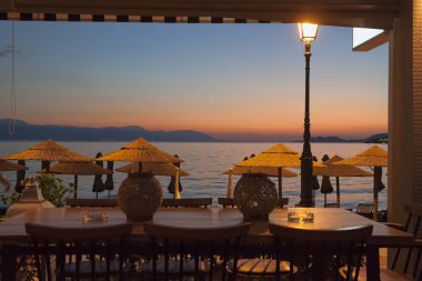 Tablo, Loutraki, Yunanistan sahildeki kafede. Akşam güneş battıktan sonra