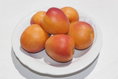 Beyaz bir tablo üzerinde beyaz bir tabakta olgun kayısı yıkanmış