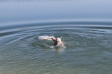Olgun Yaş sakallı biri gölde yüzüyor