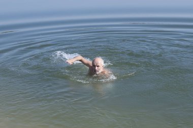 Olgun Yaş sakallı biri gölde yüzüyor