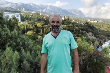 Bir sakallı bir adam portresi. Yemyeşil yeşil bitki örtüsü ve dağların