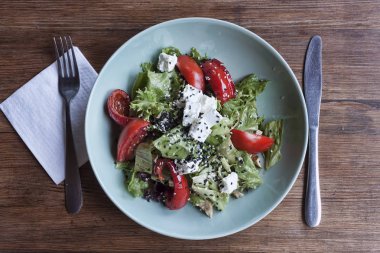 Domatesli sebze salatası, fırında dolmalık biber, peynir ve hindi eti parçaları, marul yapraklarıyla süslenmiş ve kimyon serpiştirilmiş.