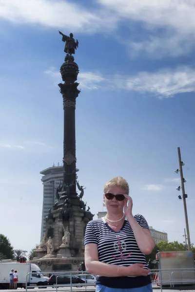 Portrait of a mature woman on the background of the Columbus Monument, built in 1888 at the Plaza of the Gate of Peace in front of the seaport of Barcelona.