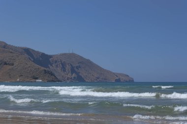 Dağlar arka planda küçük dalgalar ile deniz