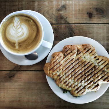 Köpük ve kruvasan karmaşık desenleri ile kapuçino bir fincan